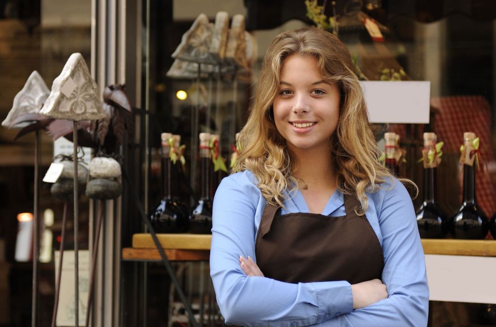 Mujer joven emprendedora sonriendo fuera de su negocio