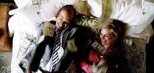 Hombre y mujer encima de una cama tirando dinero al aire