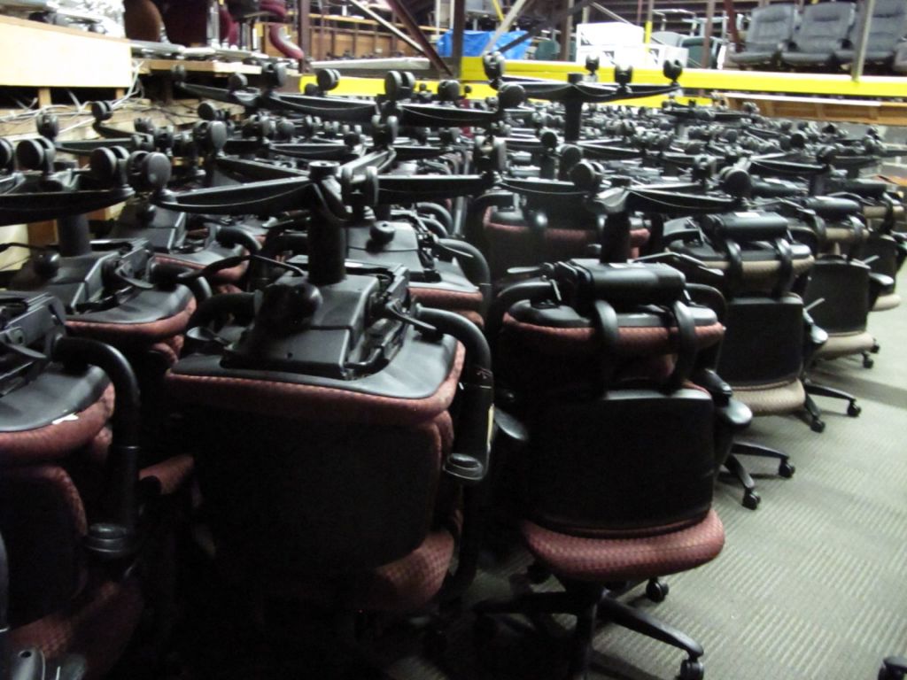 Muchas sillas de escritorio apiladas unas encima de otras en un almacen