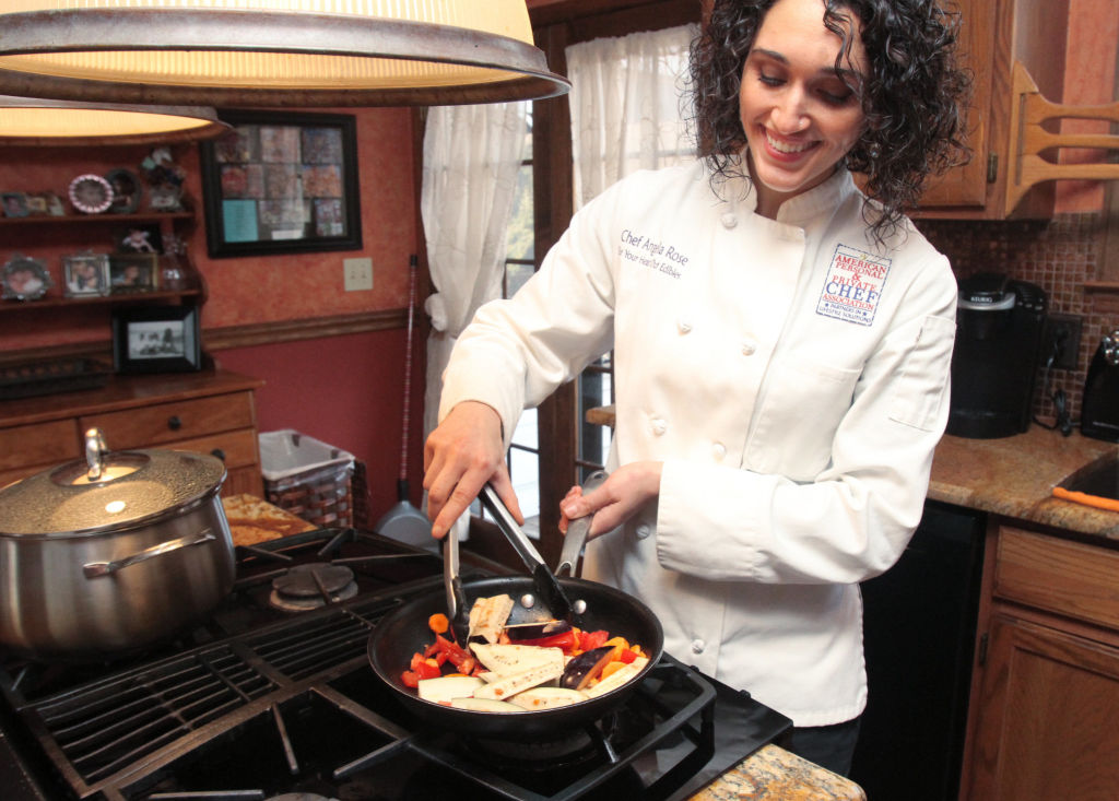 Mujer chef personal en la cocina de un cliente preparando una comida