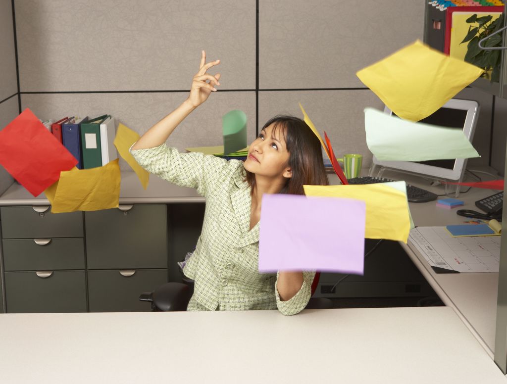 Mujer sentada en la silla de su oficina tirando unos documentos al aire despreocupada