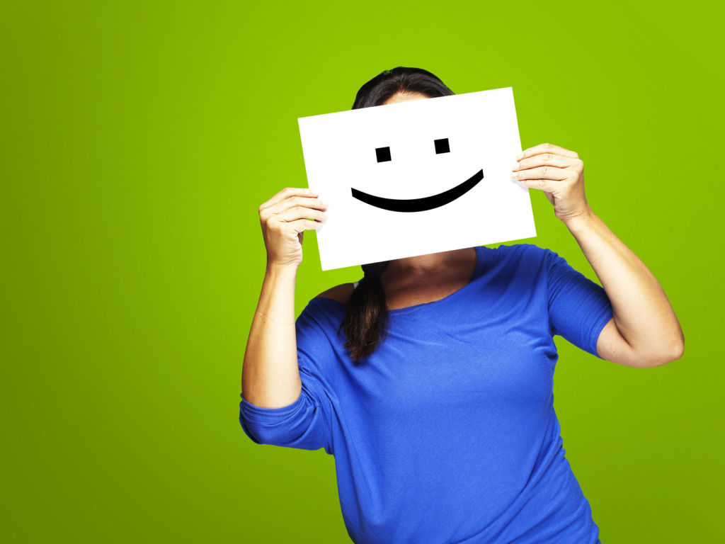 Mujer sosteniendo un folio frente a su cara con una cara sonriente
