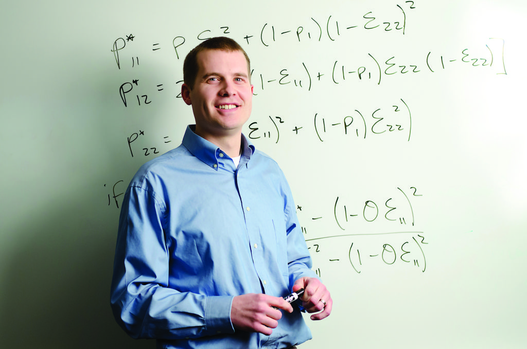 Profesor de universidad sonriendo delante de una pizarra con operaciones matematicas