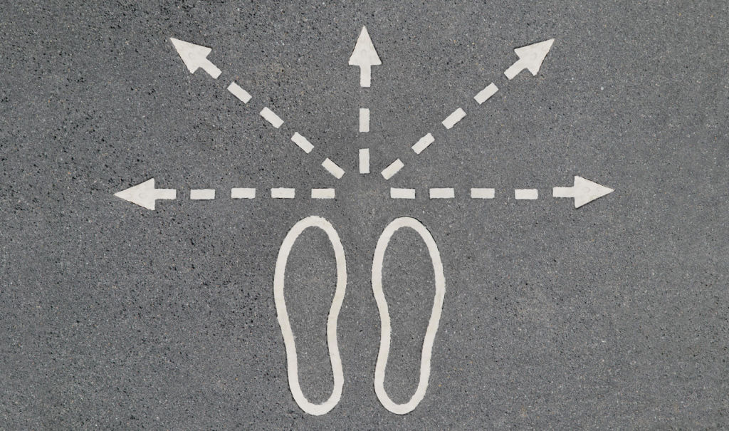 Silueta de unos pies dibujados en un suelo gris con flechas en varias direcciones para tomar varios caminos