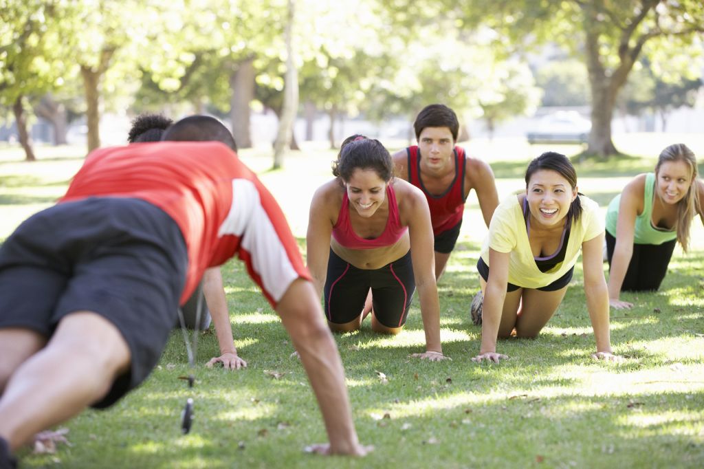 Un grupo de personas con ropa de deporte haciendo ejercicio en un parque al aire libre