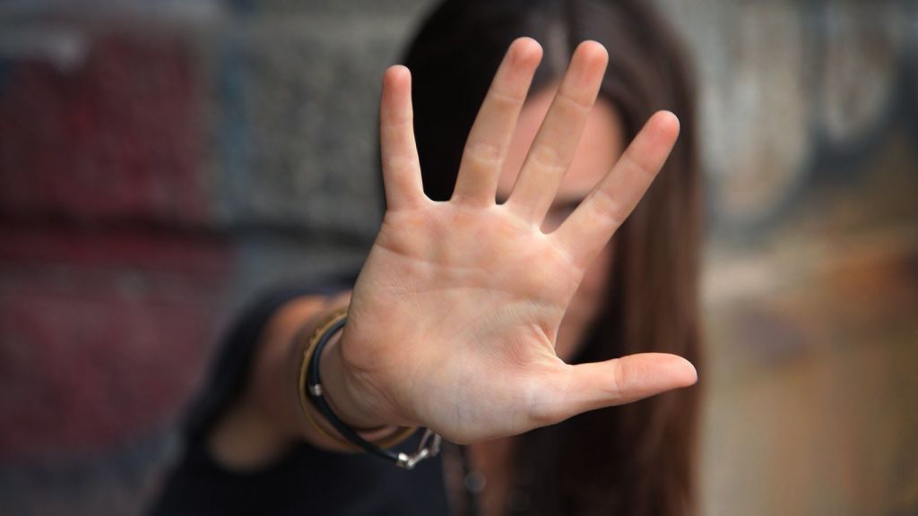 Chica joven poniendo su mano frente a su cara en senal de stop