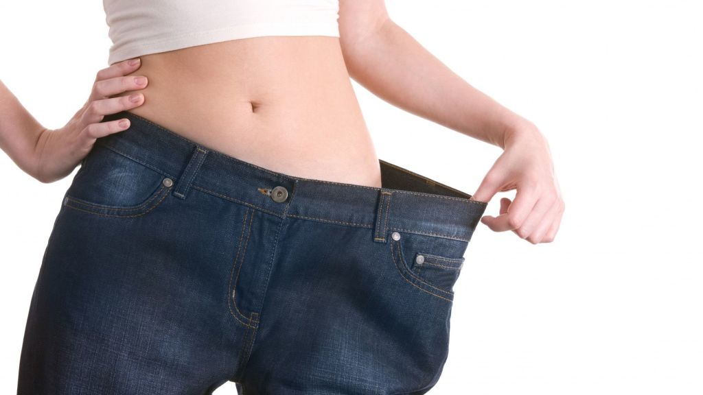 Mujer estirando un pantalon vaquero como prueba de que ha perdido peso
