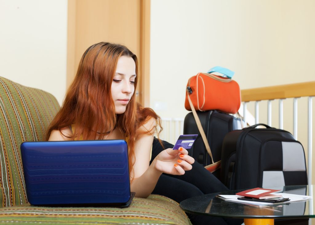 Mujer joven tumbada en su sillon con un portatil al lado y varias maletas con cosas para vender en Internet