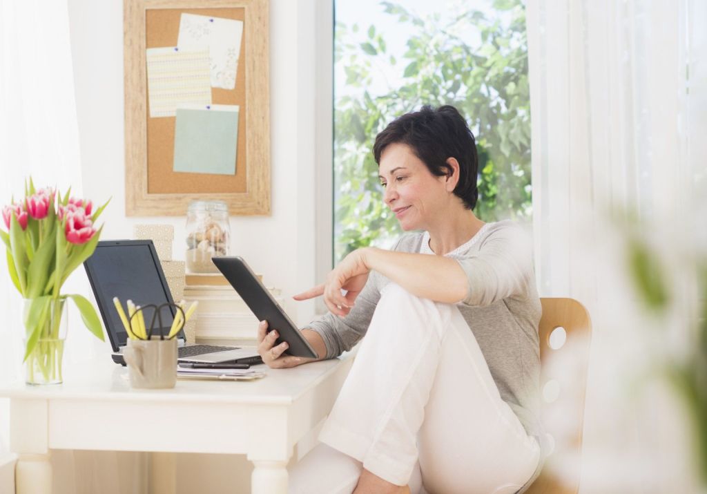 Mujer madurado en su oficina de casa mirando una tablet