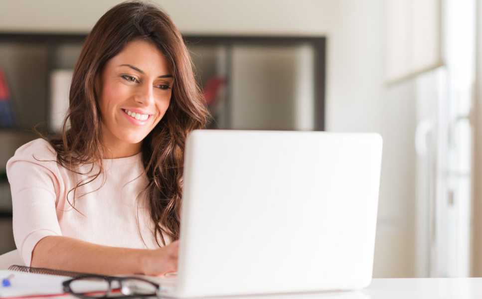 mujer sonriendo en computadora mientras trabaja