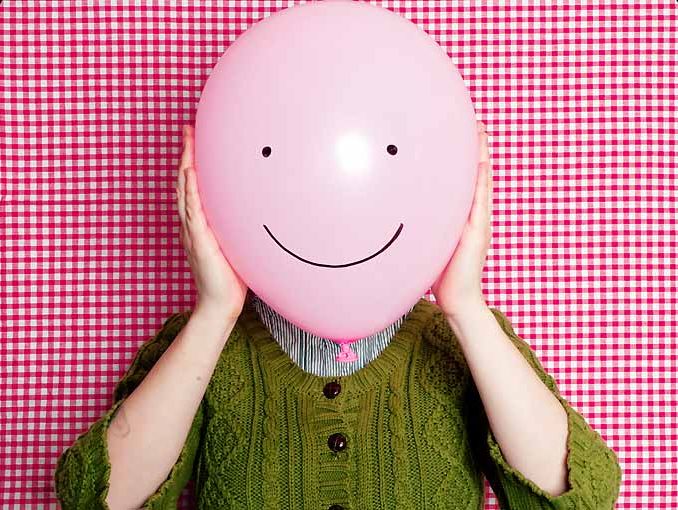 Hombre sosteniendo globo con cara feliz dibujada