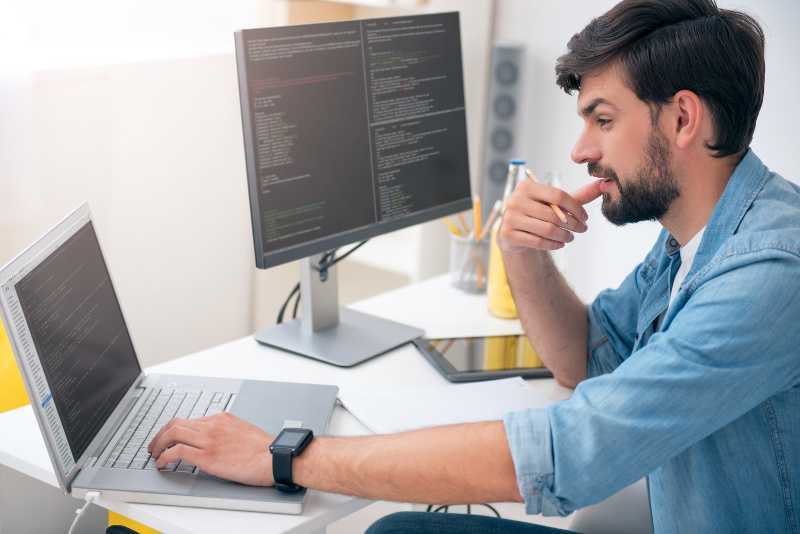 hombre mirando su computadora con la mano en al barbilla