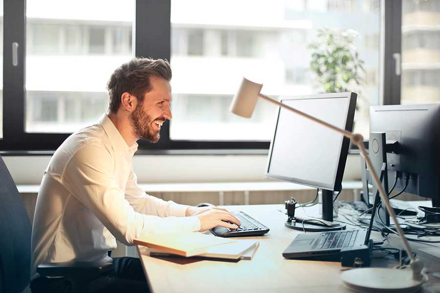 hombre en su oficina sonriendo a su computadora