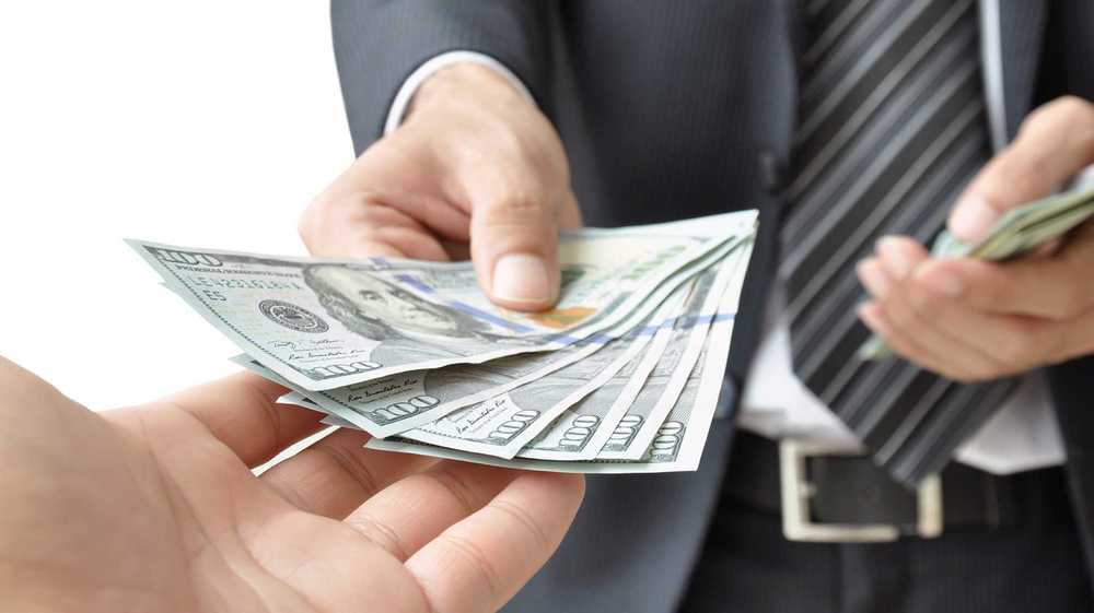 Prestamista particular dando billetes de dinero a otra persona
