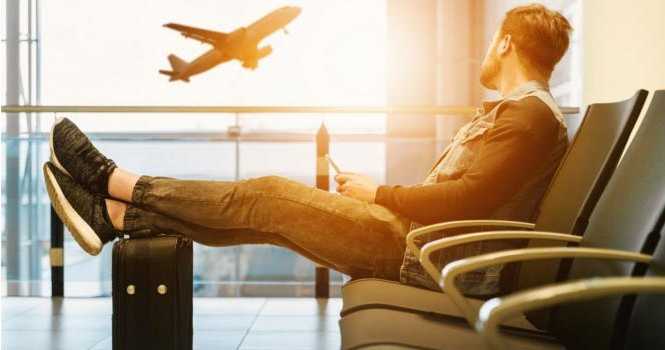 Hombre sentado en aeropuerto viendo despegar un avión