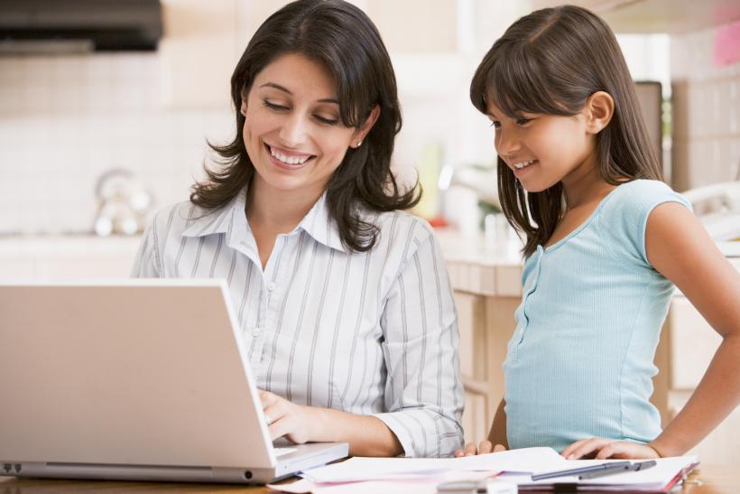 Madre en el ordenador con su hija trabajando en su negocio